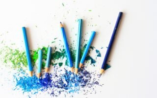 Creative display of colored pencils and vibrant shavings on a white background.