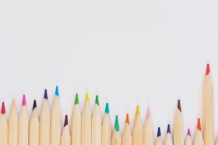A row of vibrant colored pencils aligned on a white background, providing ample copyspace.